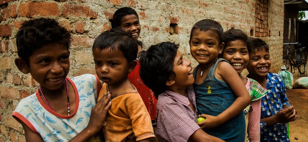 Group of smiling children playing joyfully outside a brick building in Ranchi, India.