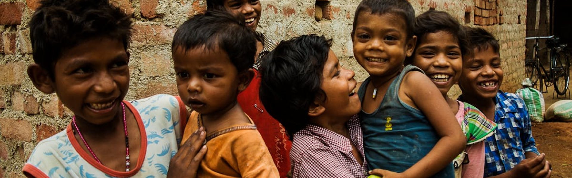 Group of smiling children playing joyfully outside a brick building in Ranchi, India.