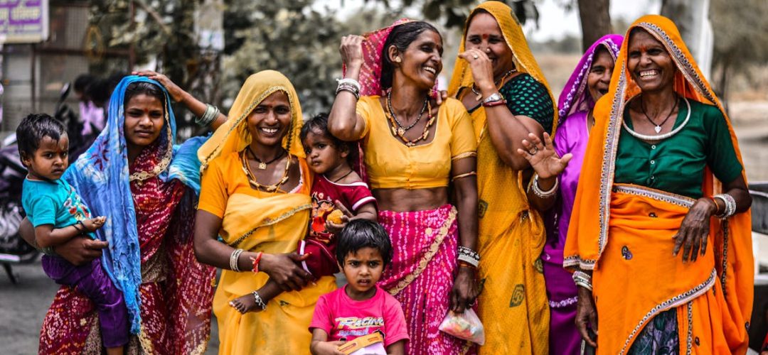 A lively group of women and children in traditional Rajasthani attire, showcasing vibrant culture and joyful expressions.