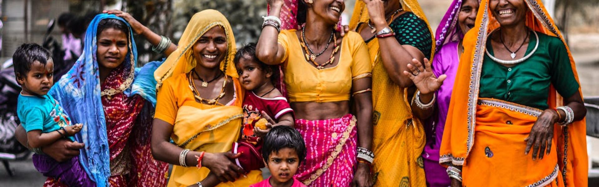 A lively group of women and children in traditional Rajasthani attire, showcasing vibrant culture and joyful expressions.